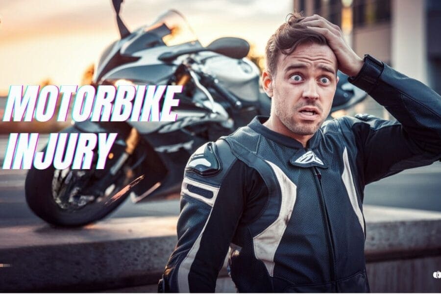 A man in a motorcycle suit looks surprised or worried while holding his head. A motorcycle is parked in the background. The words "Motorbike Injury" are written on the left side of the image.